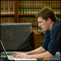 Male student working on laptop in library